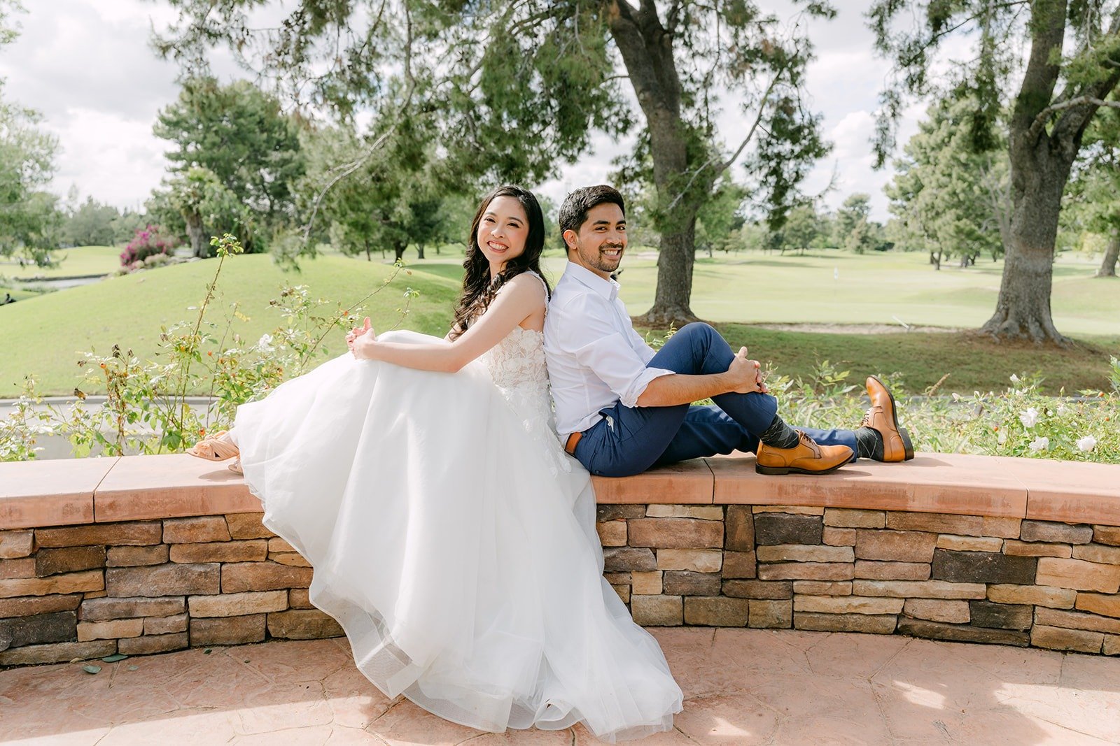 Natalie and Mark relaxing on the stone wall in the sunshine, photographed by One and Only Production