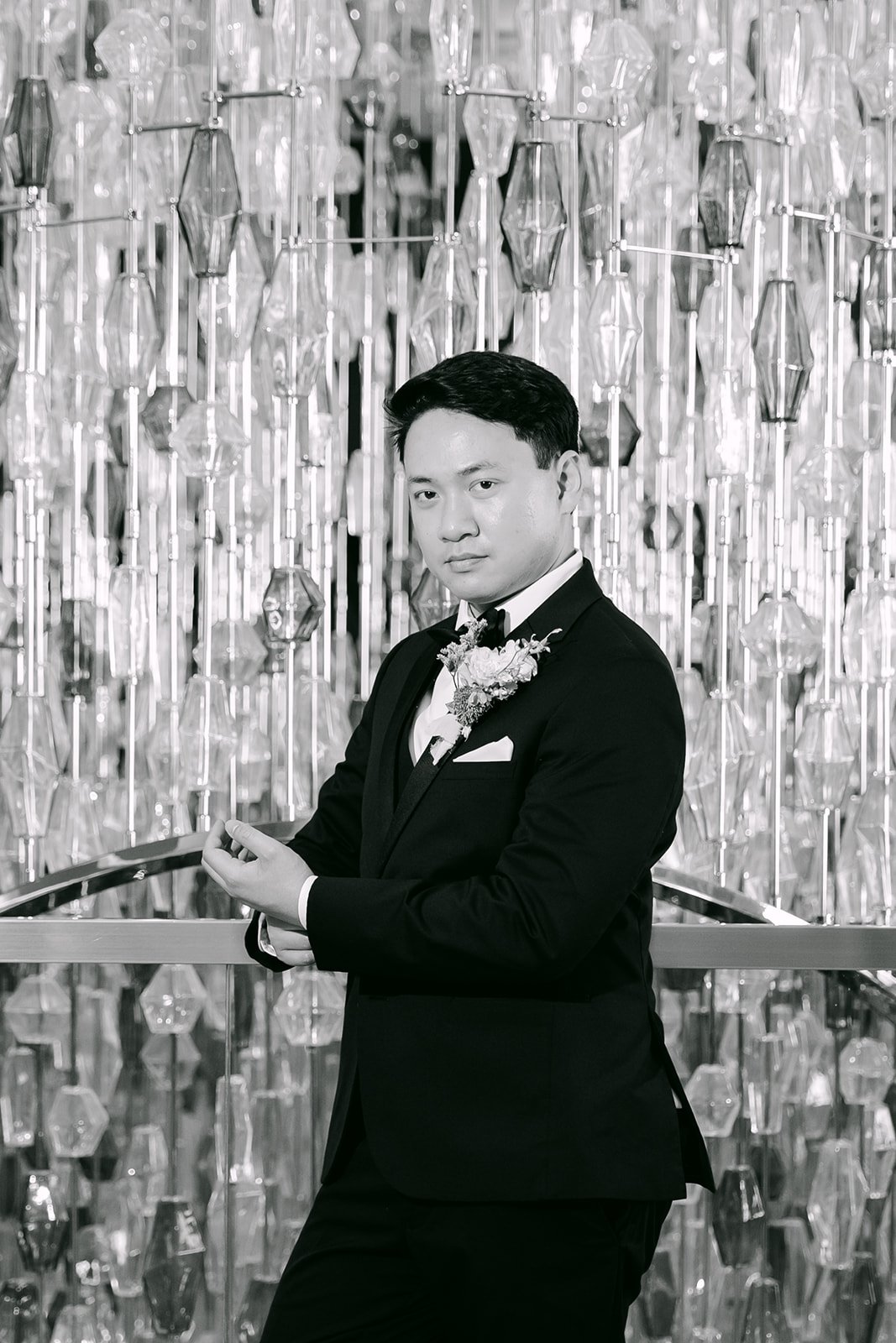 Black and white portrait of the groom in front of the lobby chandelier