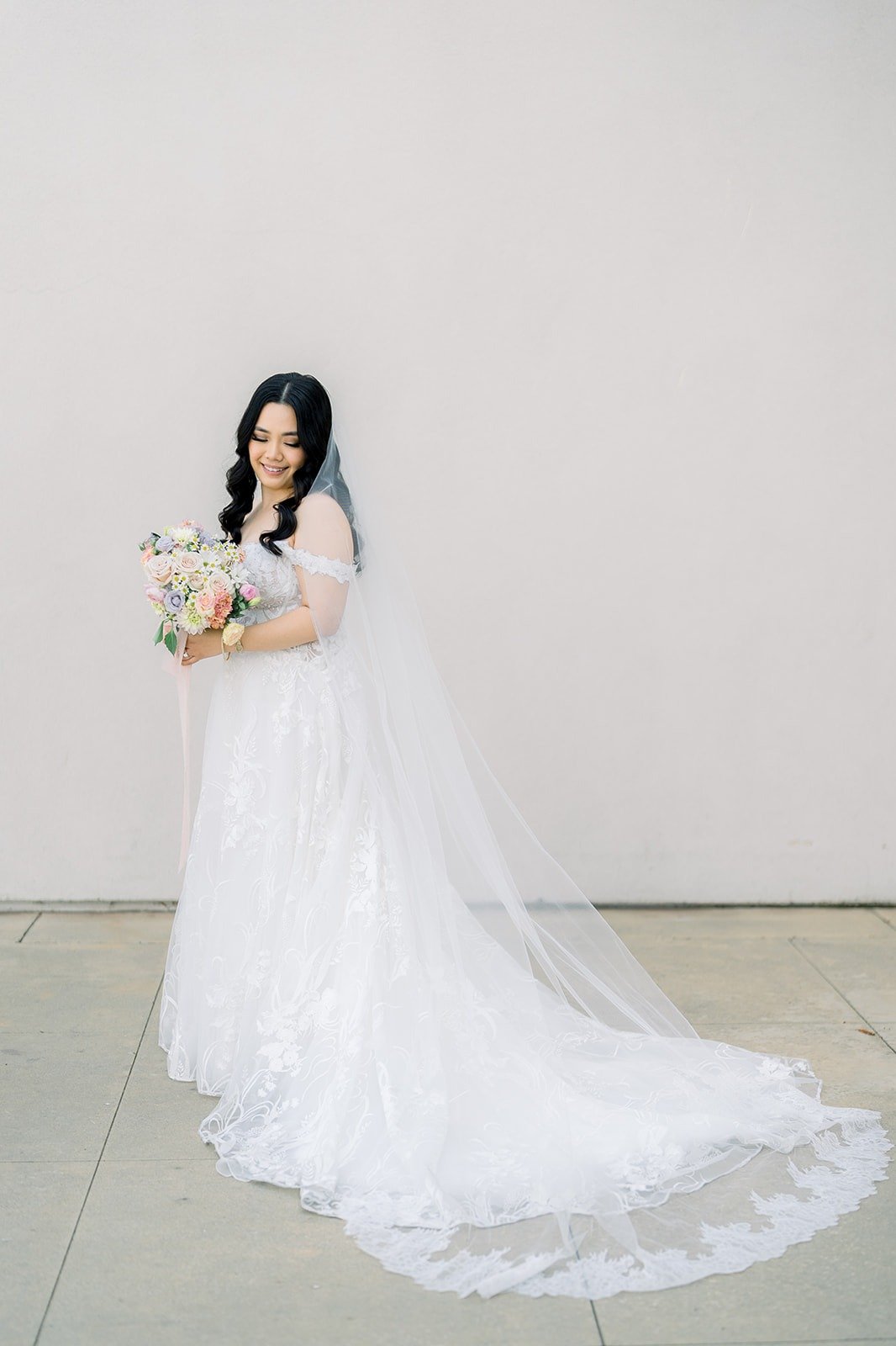 Francesca in her gown and cathedral veil holding a pastel bouquet