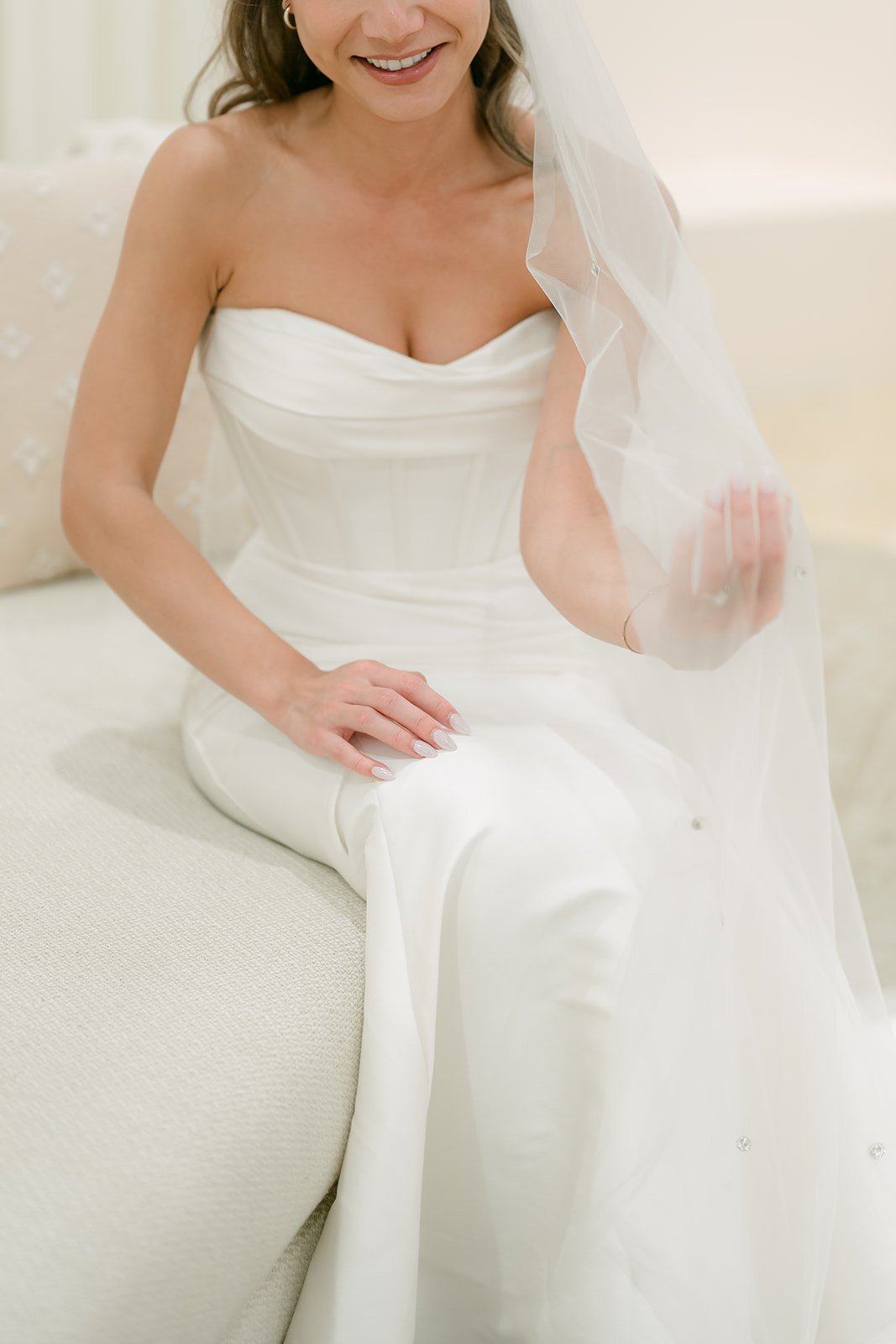 Bride sitting in her gown with her veil draped over one shoulder