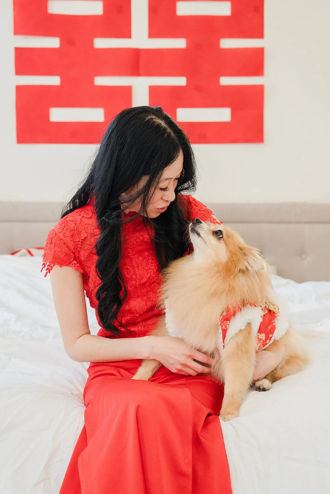 Valerie holding Kohmie under a double happiness papercut.