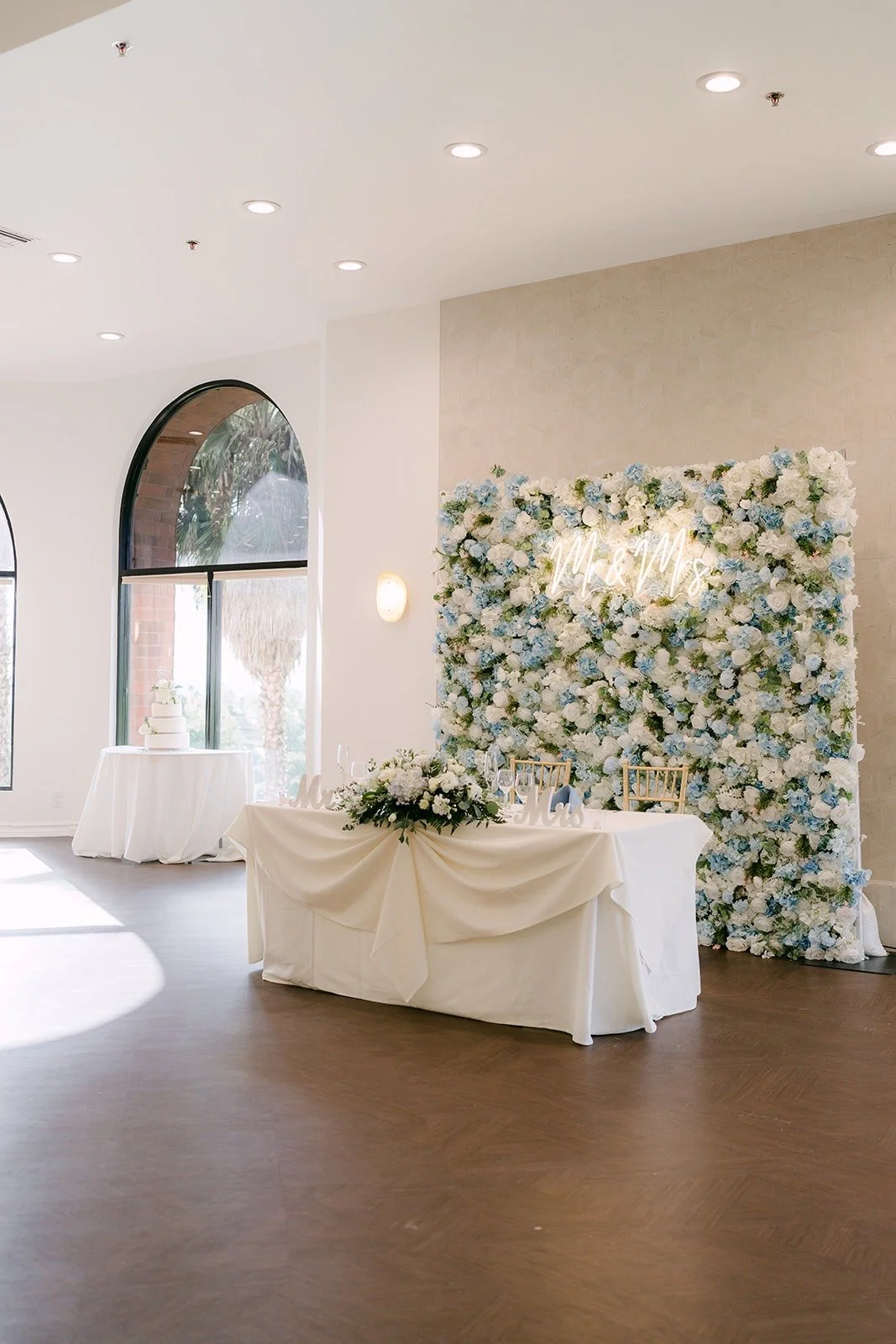 The sweetheart table in front of a white and blue flower wall