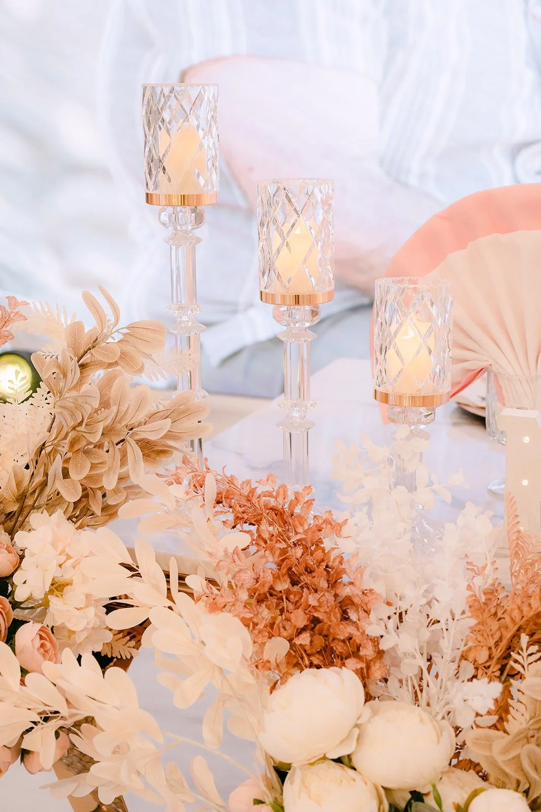 Ivory and blush florals with candles on a reception centerpiece