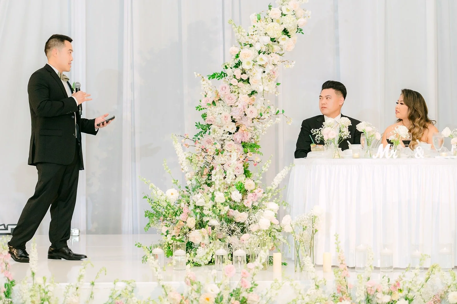 A speech beside the floral sweetheart table