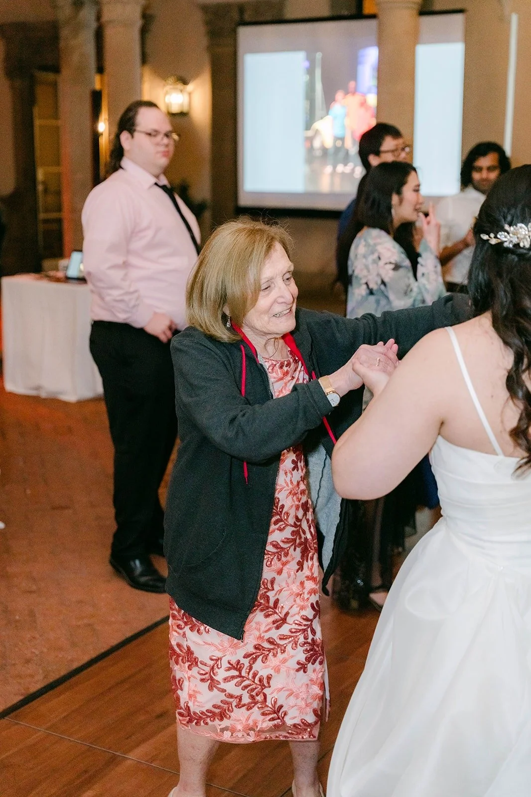 Saira dancing with guests in front of the projector screen