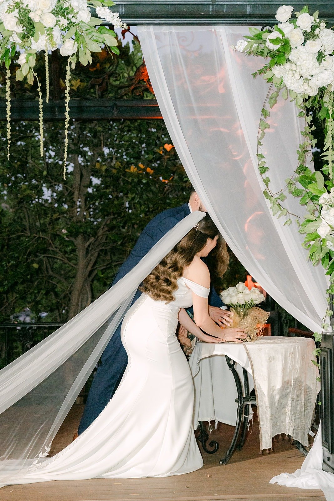 Mariana and Danny placing white roses for the Virgin Mary during the ceremony