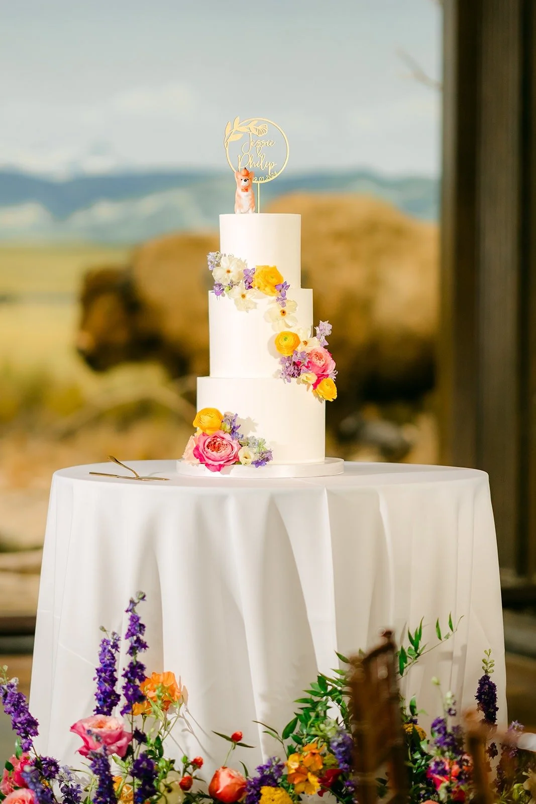 The tiered wedding cake with fresh florals in front of the bison diorama