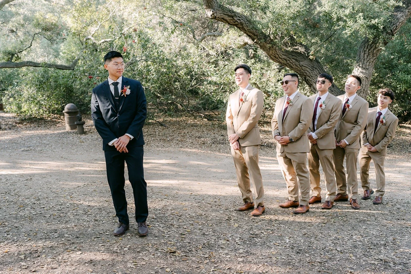 Robert walks toward his groomsmen in tan suits on the trail