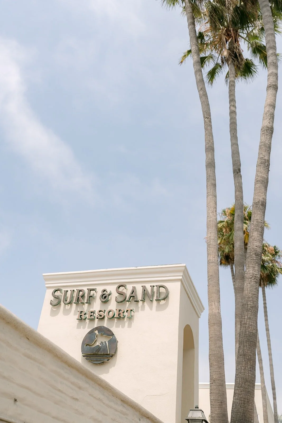 The Surf & Sand Resort sign framed by tall palm trees