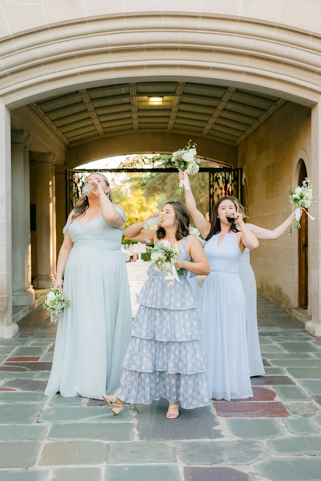 Bridesmaids dancing into the courtyard with their bouquets