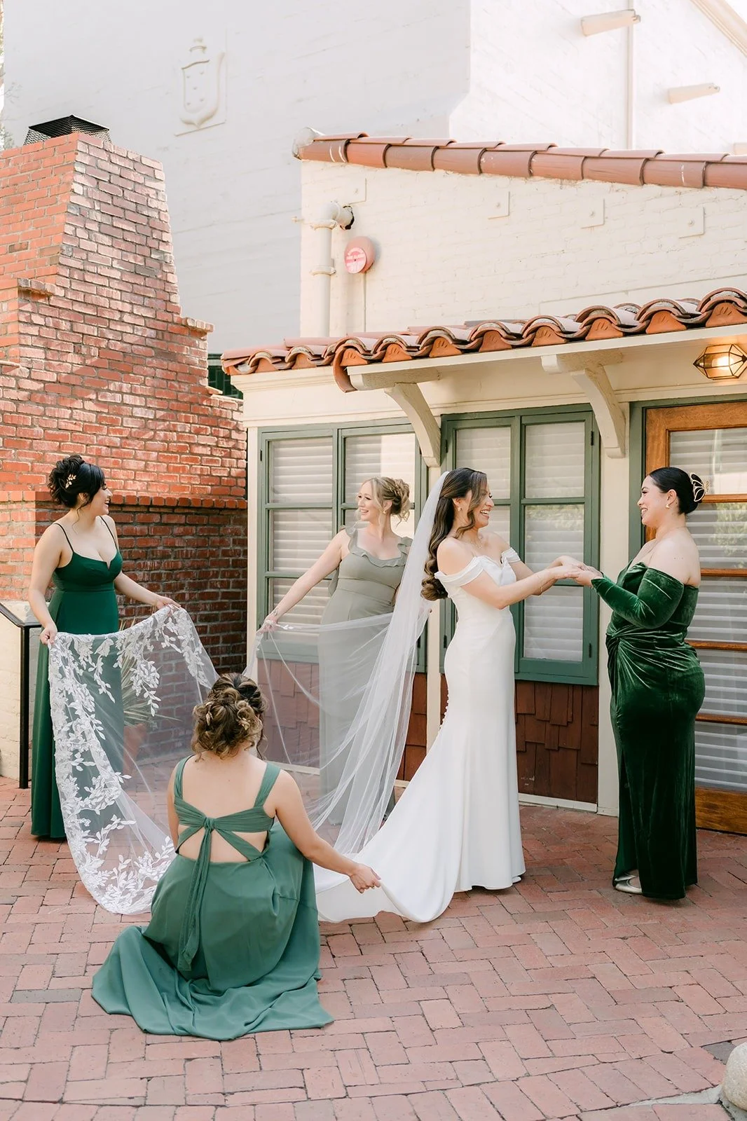 Bridesmaids fluffing Mariana's cathedral veil outside the bridal cottage at Padua Hills Theatre