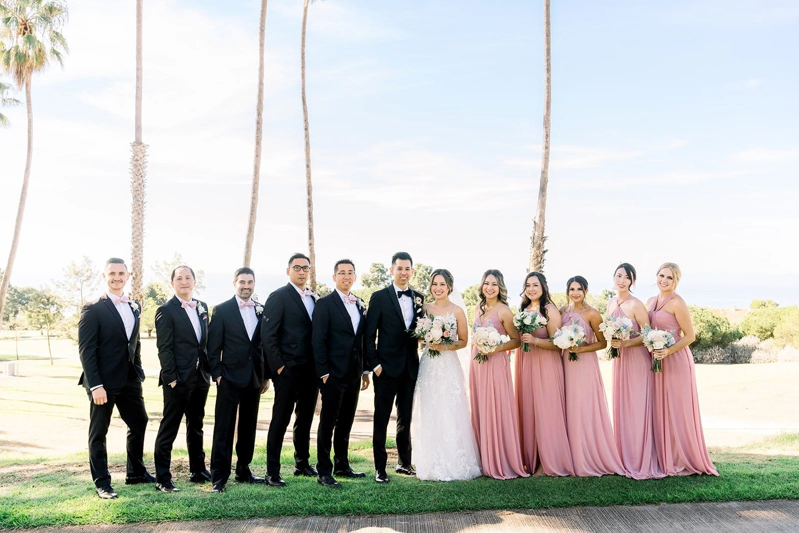 The full wedding party lined up beneath the palm trees