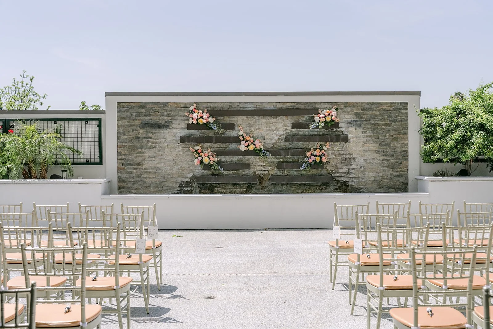 Gold chairs set facing the stone wall for the ceremony at Courtyard Monterey Park.