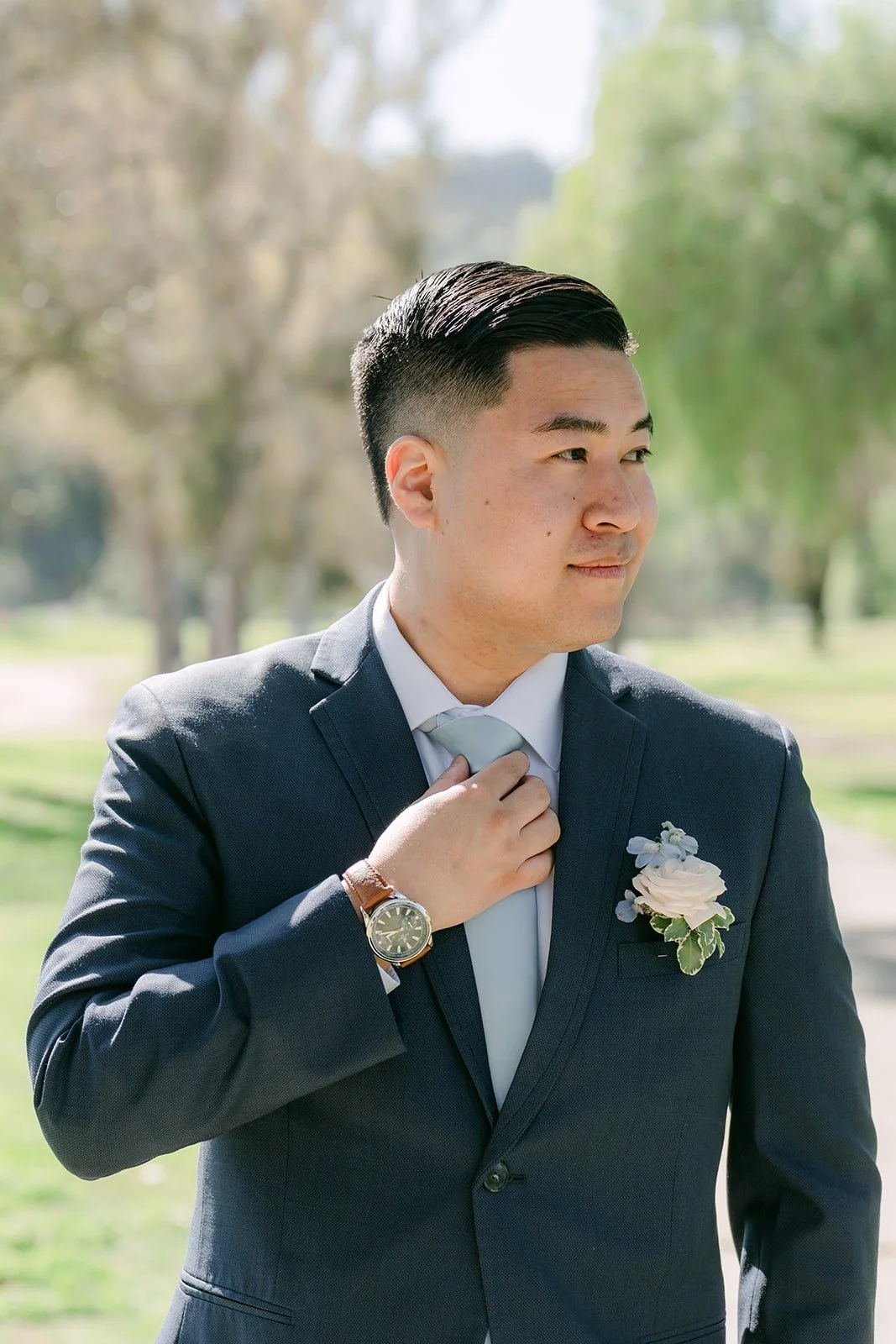 Jordan adjusting his tie on the golf course, photographed by One and Only Production