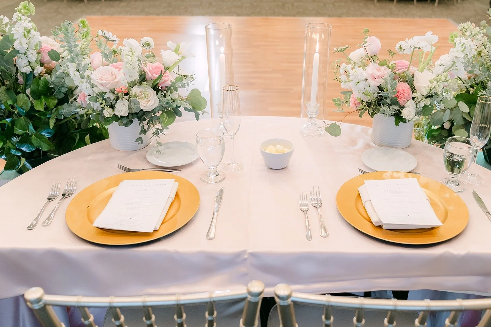 Gold chargers and folded napkins on a long reception table