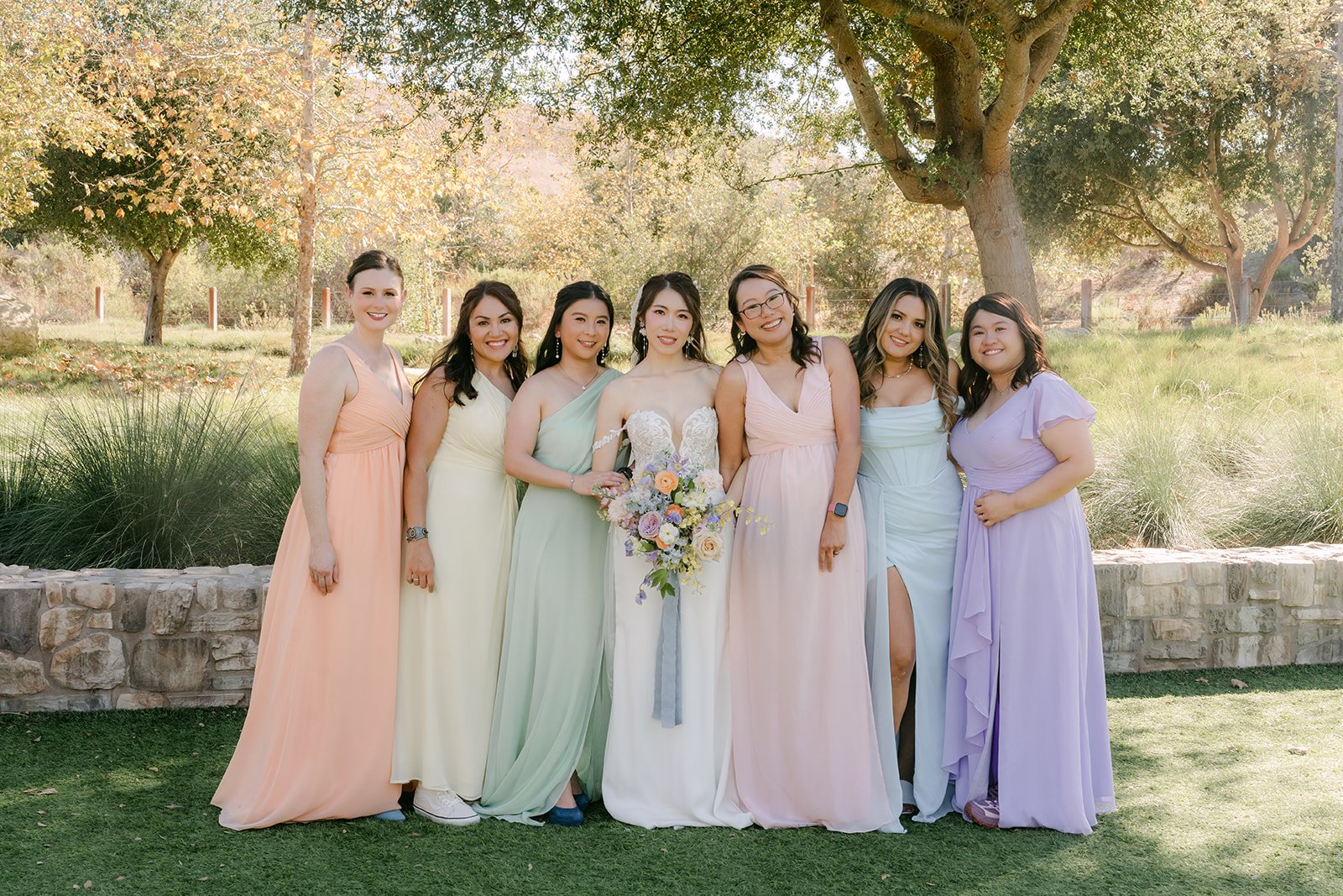 Christie with her six bridesmaids in sky blue, lilac, peach, pistachio and lemon dresses.