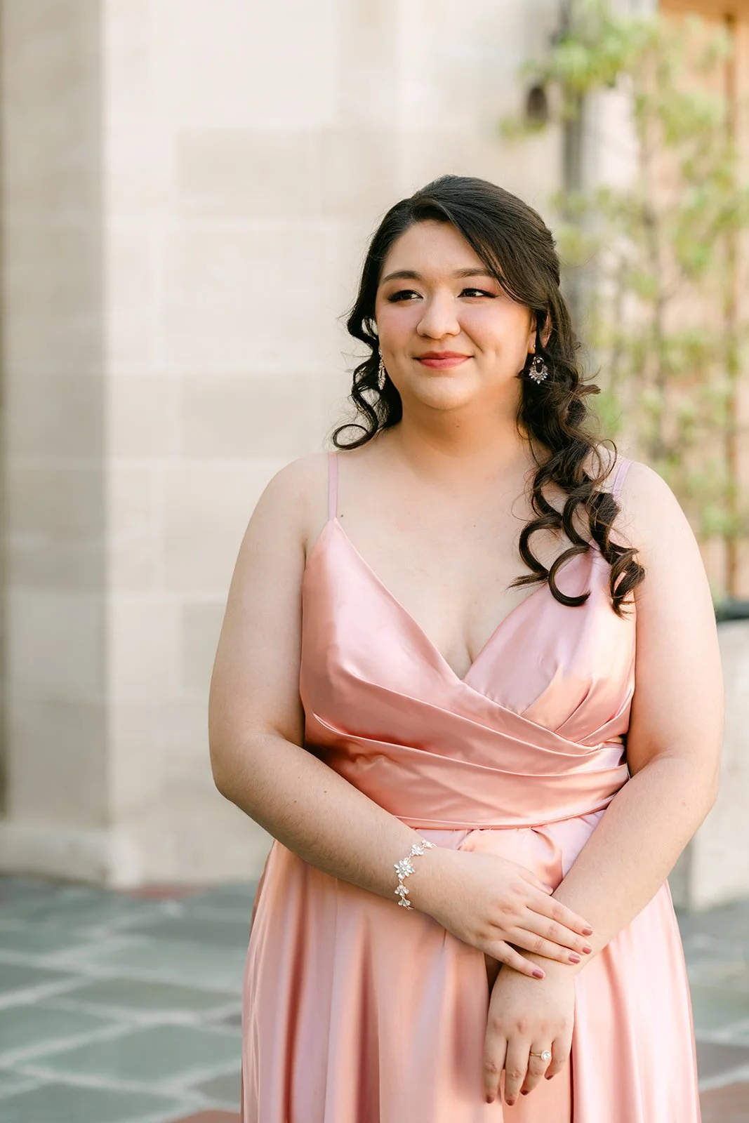 Portrait of Saira in blush satin in front of the mansion's limestone walls, photographed by One and Only Production.