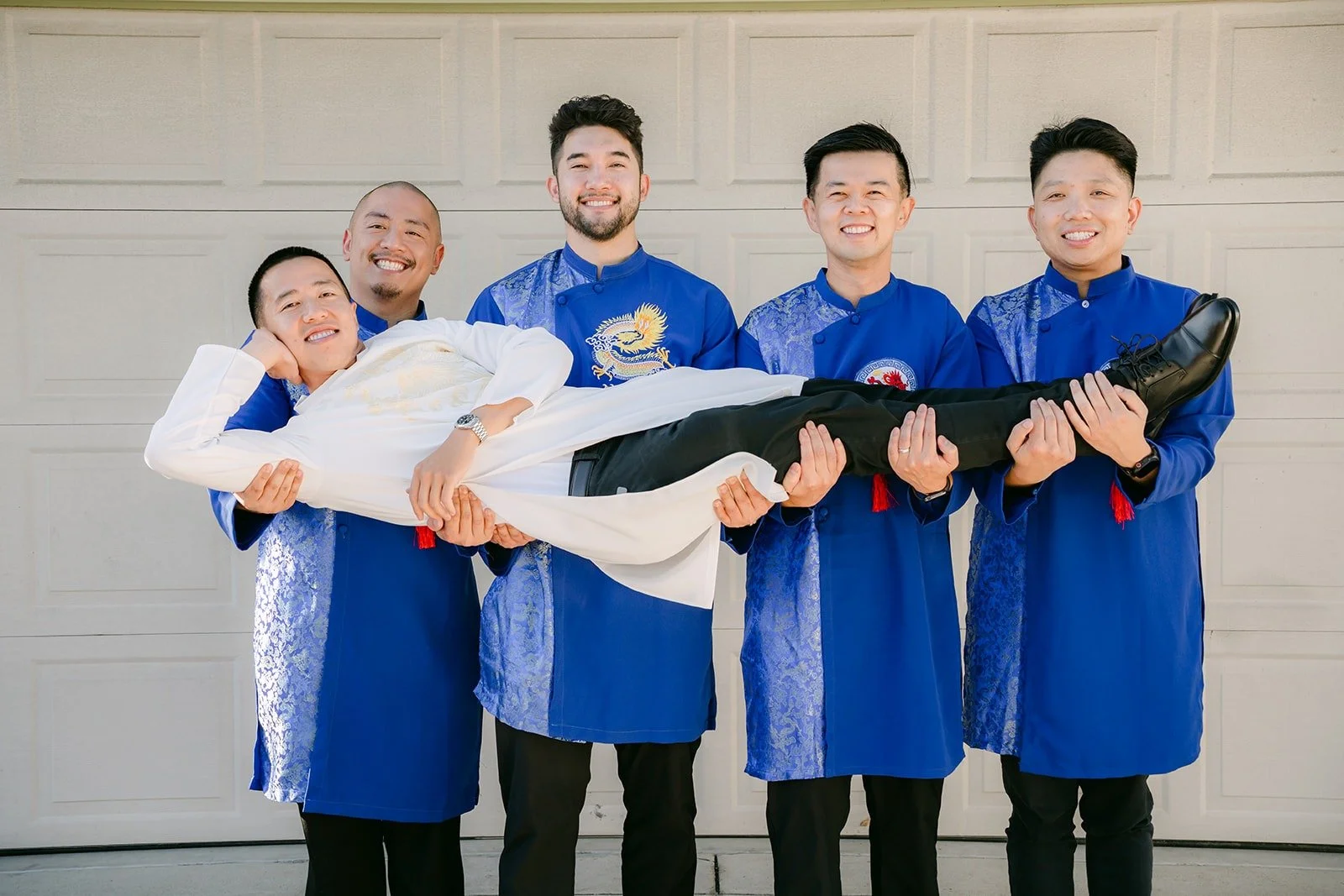 Kevin's groomsmen lift him sideways for a playful photo