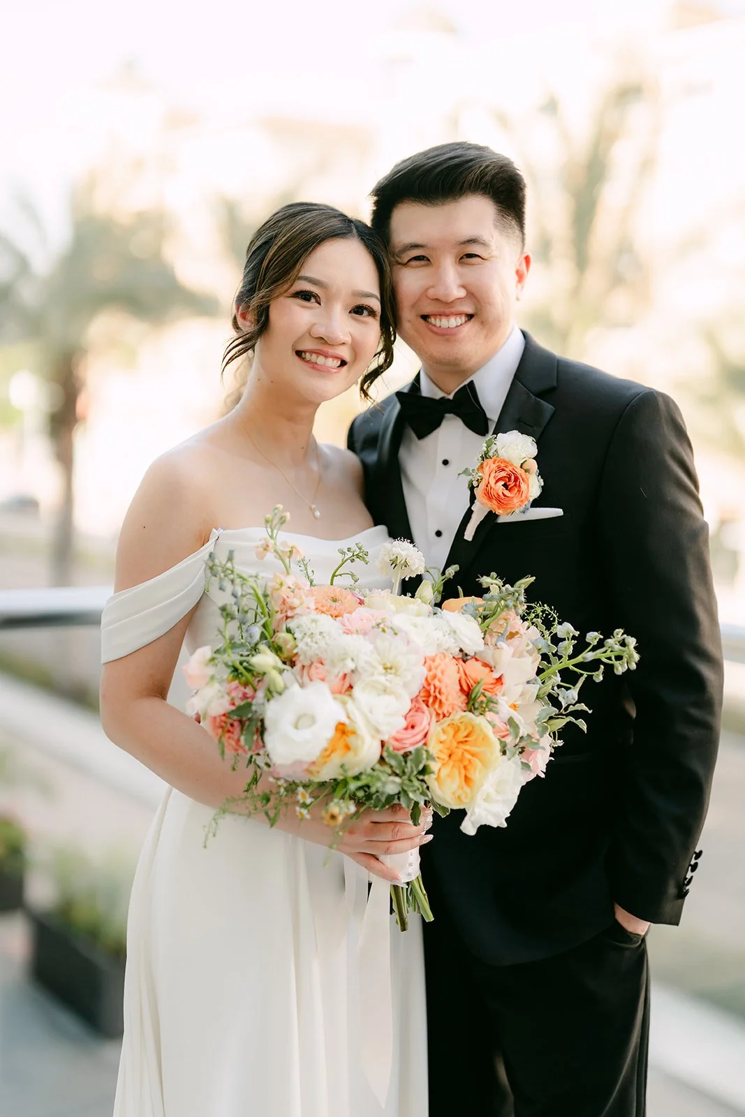 Amanda and San smiling together with her bouquet.