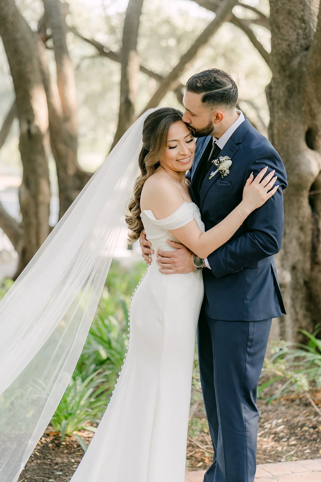 Danny kissing Mariana's forehead under the olive trees