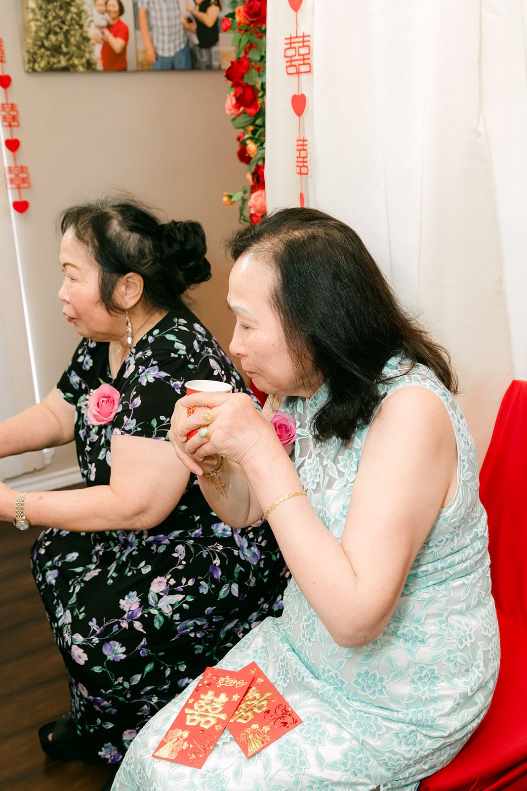 Two aunties laughing with a red envelope.