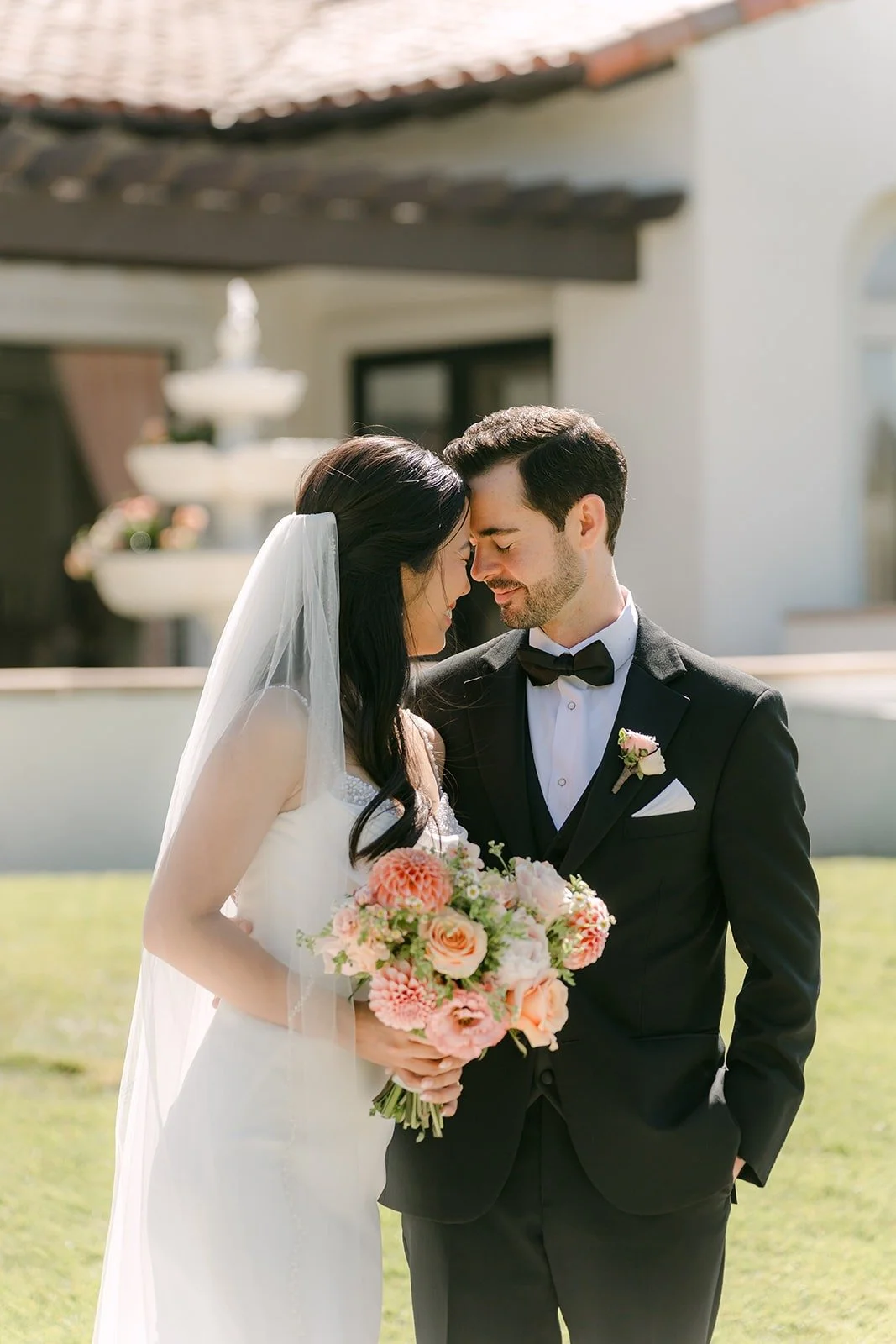 Stephanie and Kevin leaning in close with her bouquet between them