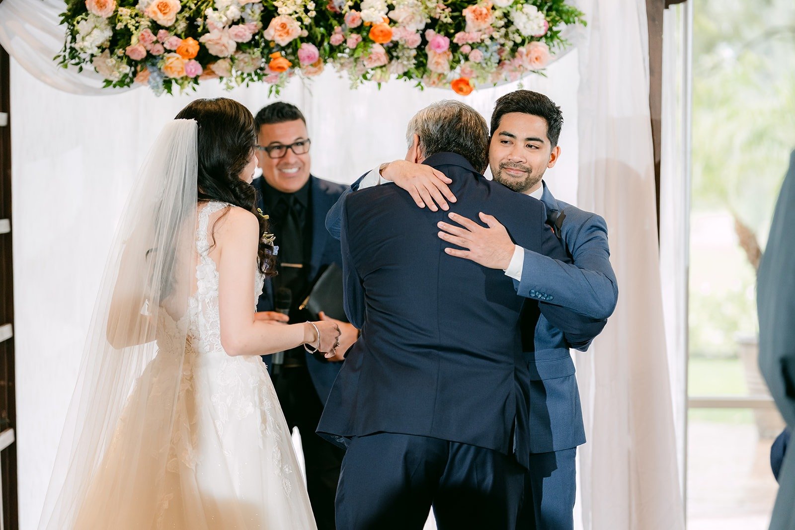 A family member hugging Mark at the arch as Natalie arrives at the ceremony