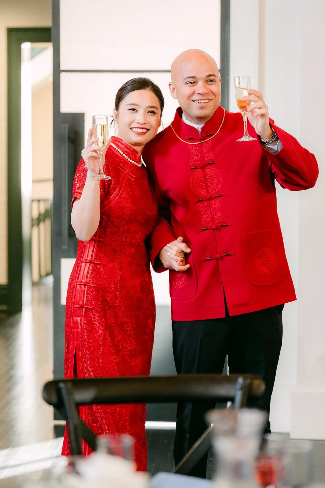 Elisa and Brandon raise their hands beside the cake