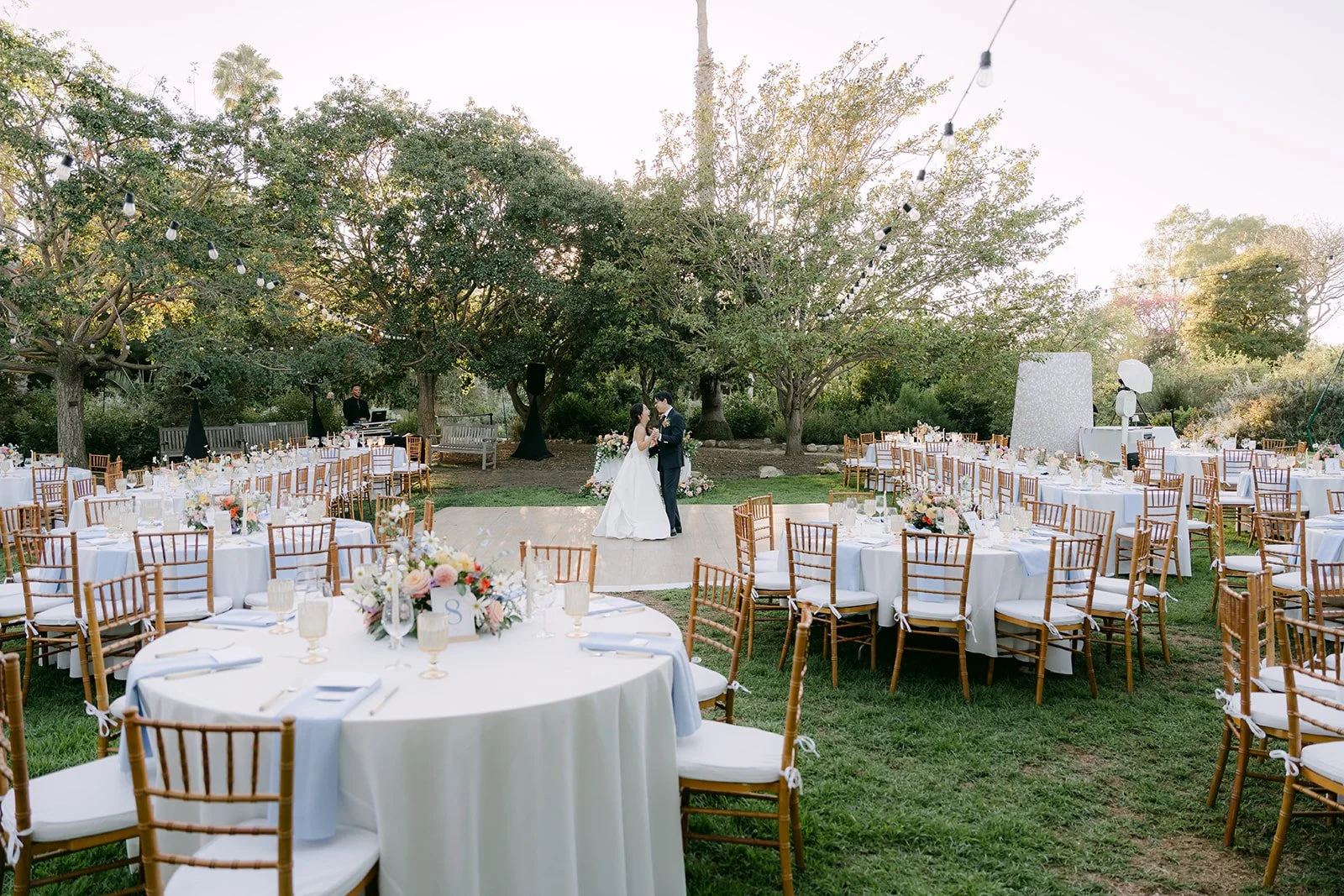 Reception tables set beneath the garden trees