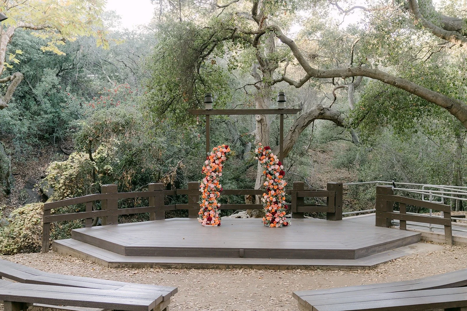 The ceremony stage and floral arch set among the oaks at Oak Canyon Nature Center