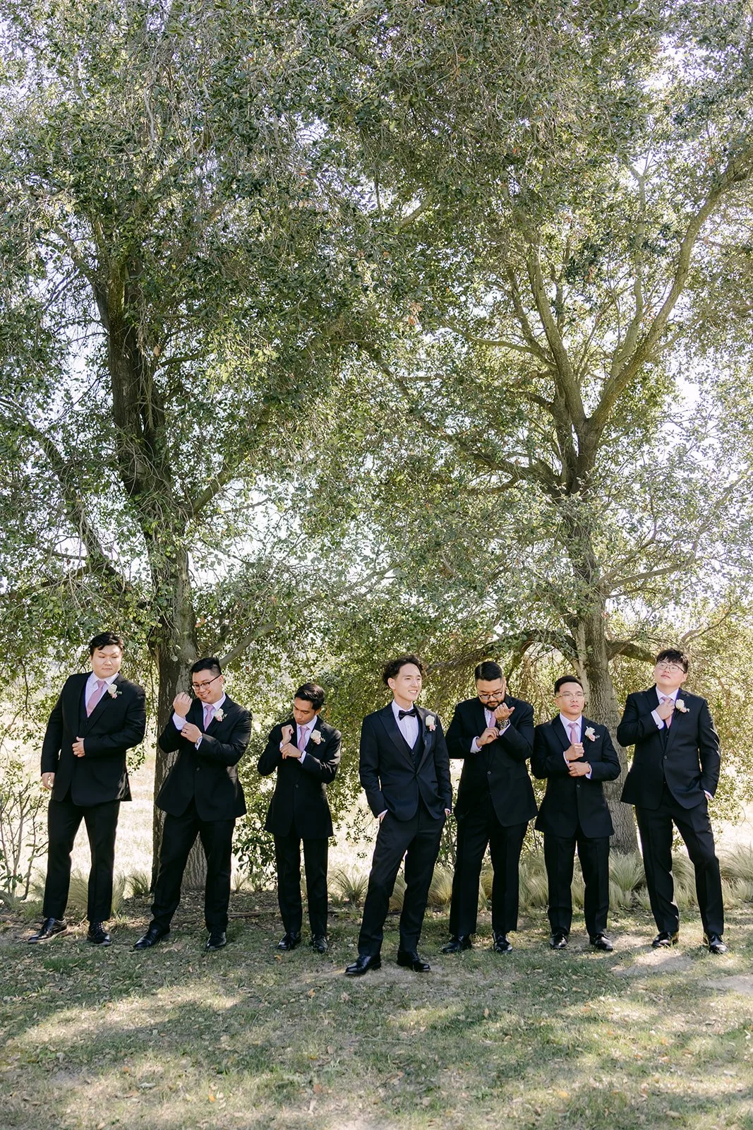 Groom and groomsmen celebrating under the oak trees