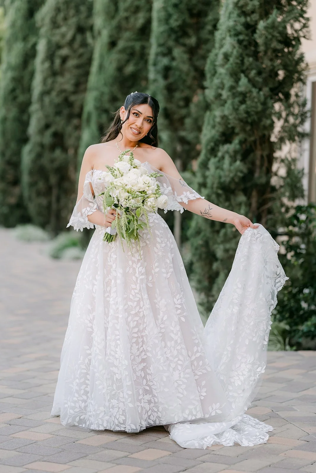 Fernanda in her gown and cathedral veil among the cypress trees.