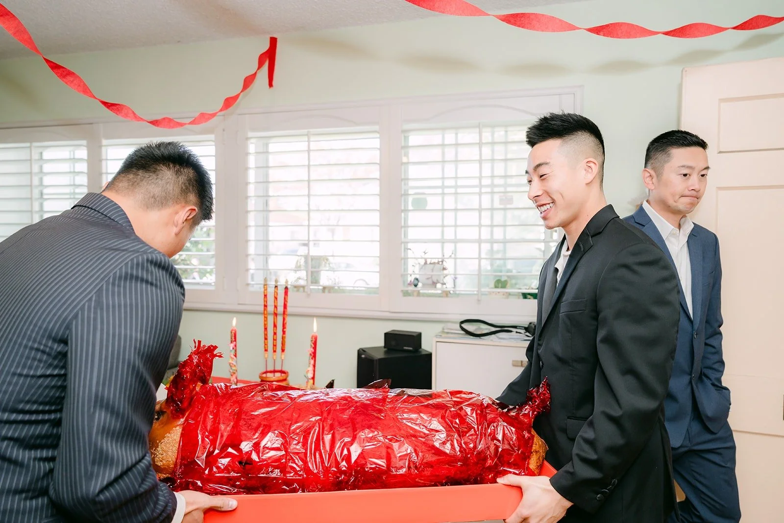 Groomsmen carry in a red gift tray at the start of the door game