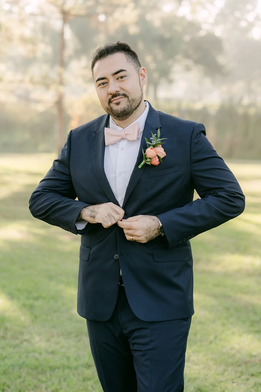 James buttoning his navy jacket, pink boutonniere on the lapel