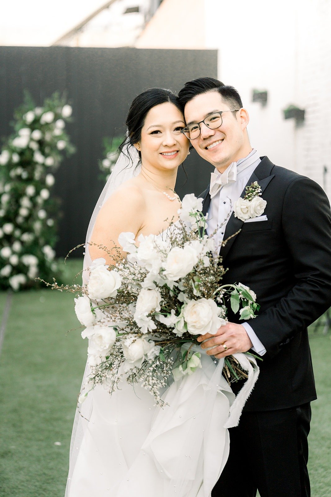 Cindy and Alex smile close together with her bouquet