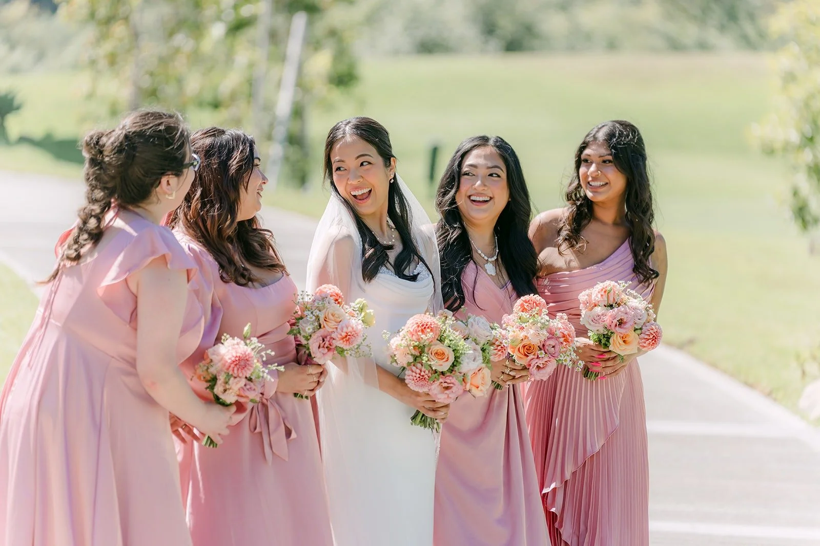 Stephanie laughing with her bridesmaids in dusty pink dresses