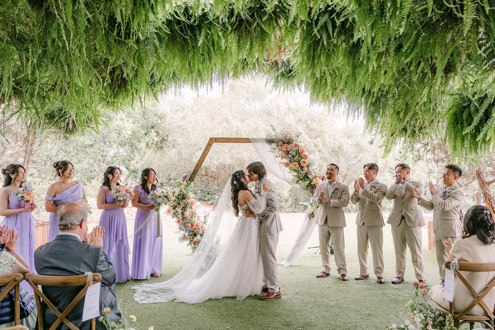 First kiss under the hexagon arch with the wedding party cheering