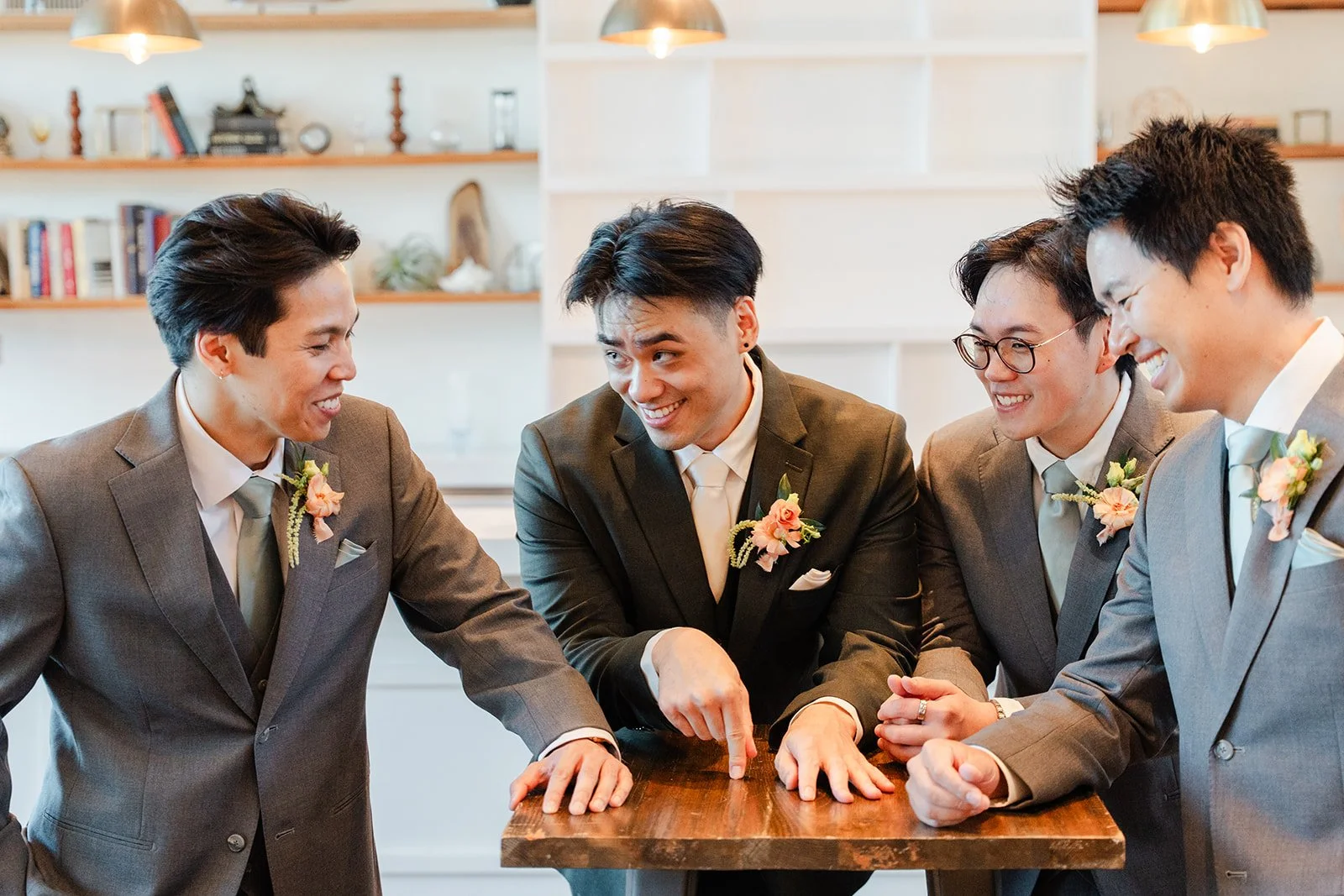 Groomsmen laughing around a table while getting ready