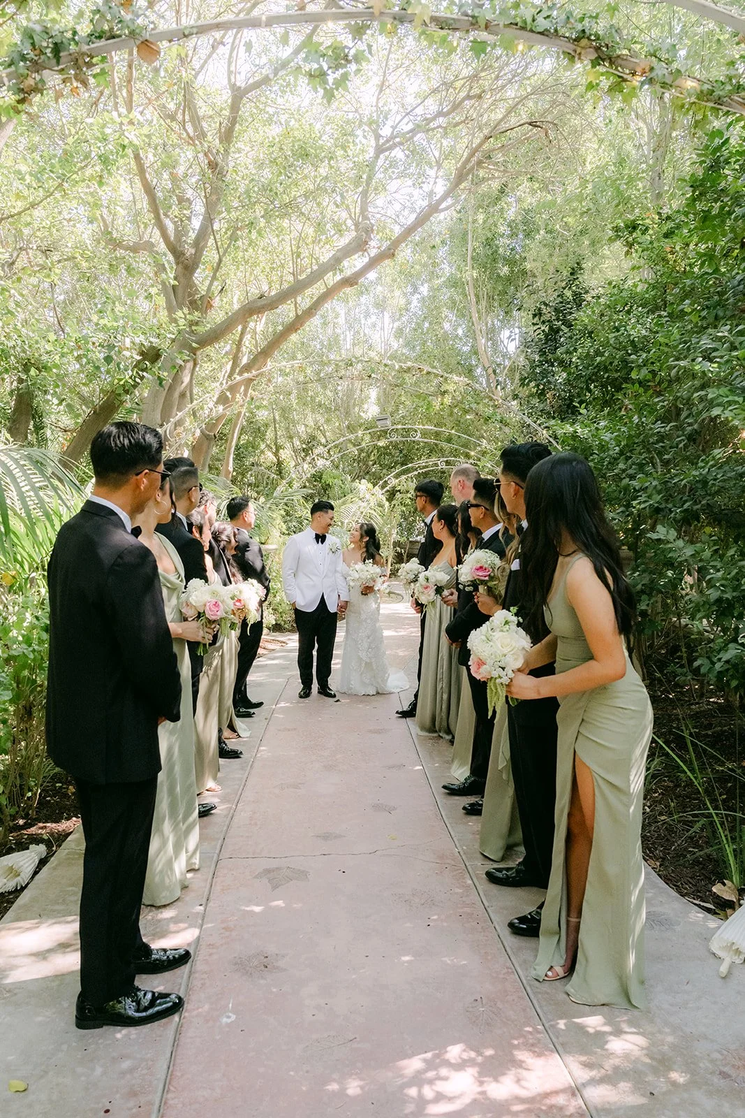 Caryl and Nicole walking toward their wedding party on a garden path at Eden Gardens.