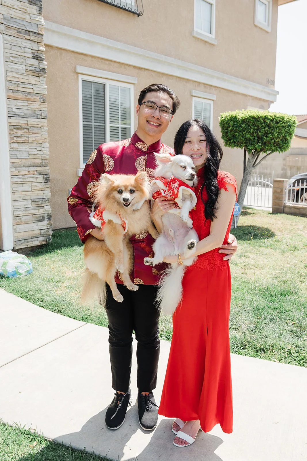 Valerie and Danny holding their dogs outside the house.