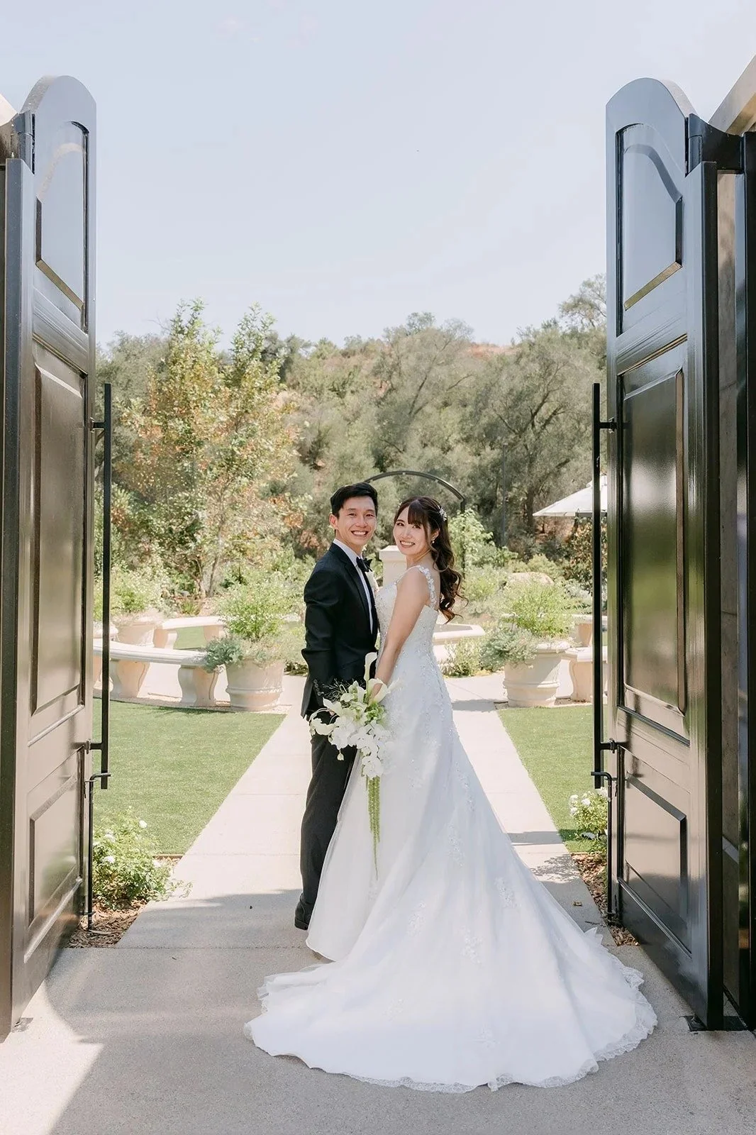 Tyler and Marina standing together between the open iron gates