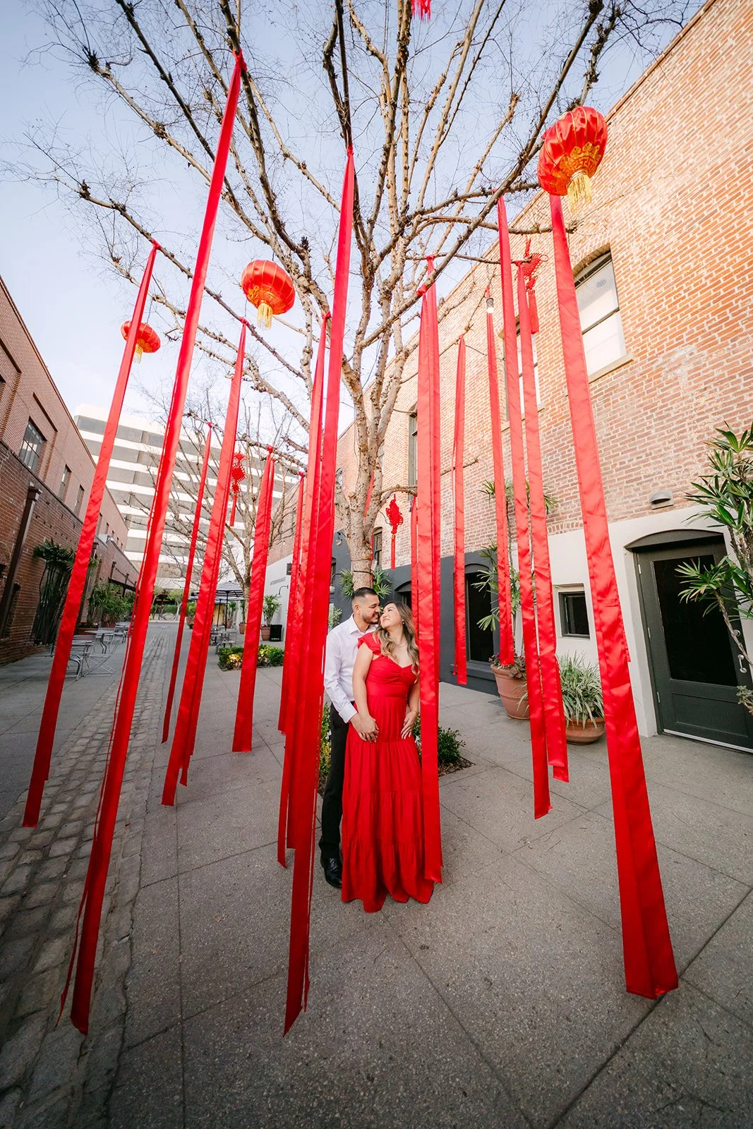 Linh walks among tall red ribbon streamers and lanterns.