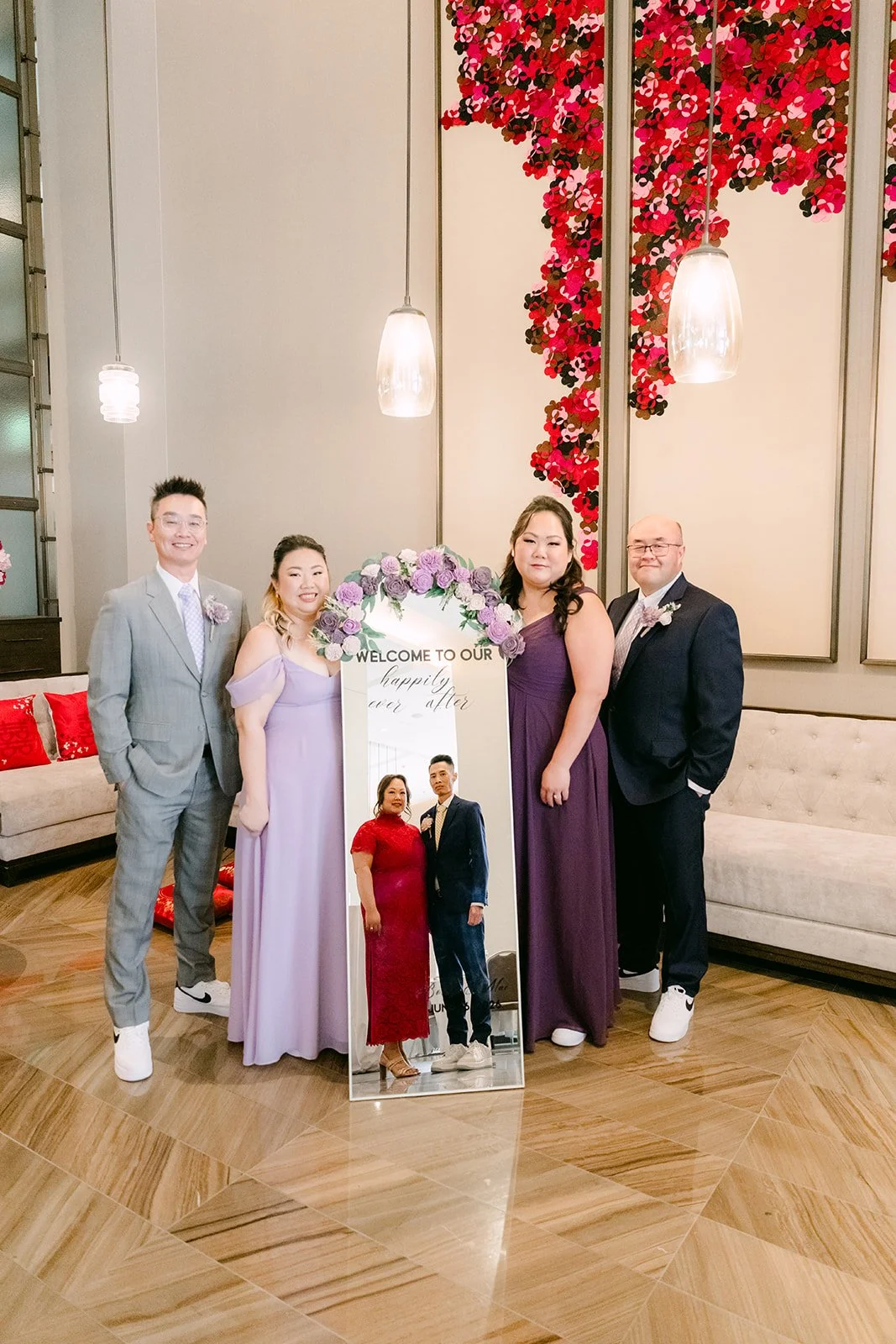 The wedding party in front of the red floral wall.