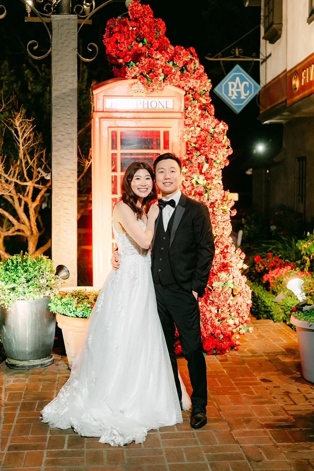 Valerie and Jason at night in front of the lit red phone booth at Five Crowns in Corona del Mar