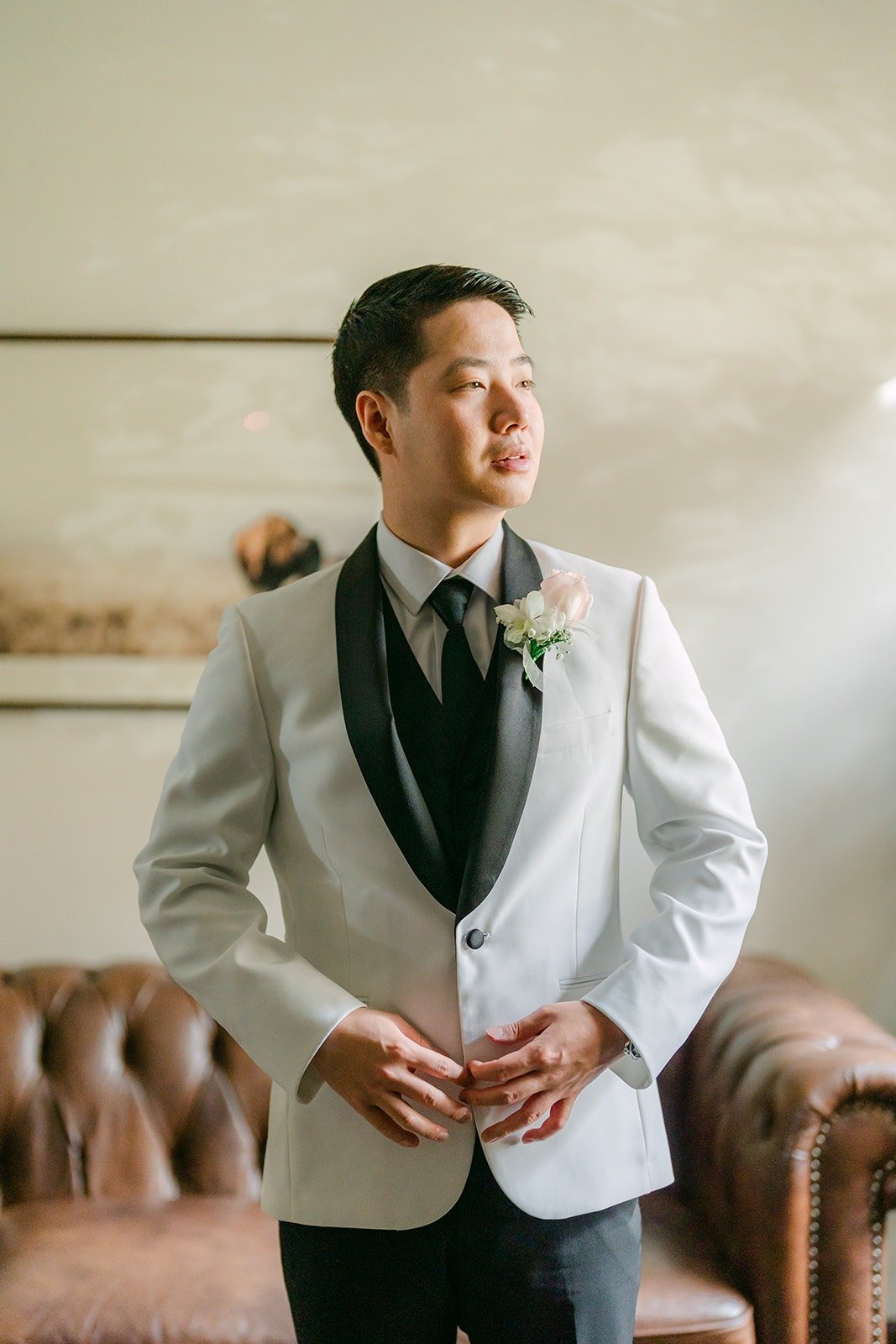 Chungman buttoning his white tuxedo jacket
