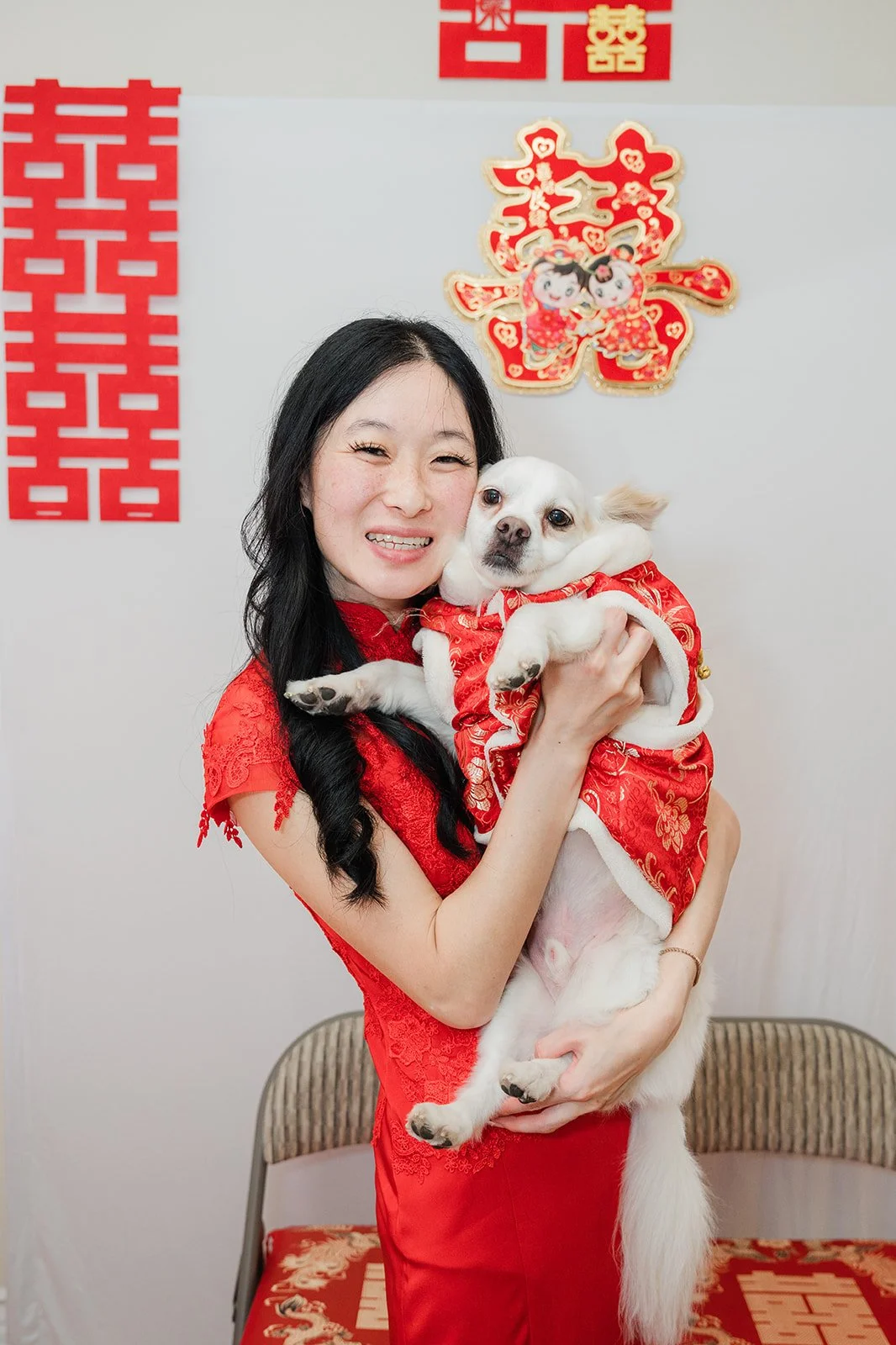 Valerie holding Kohmie beside red papercuts, photographed by One and Only Production.