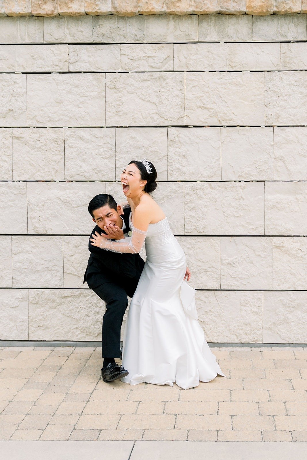 Steven hugs Jacinda against a stone wall as they both laugh