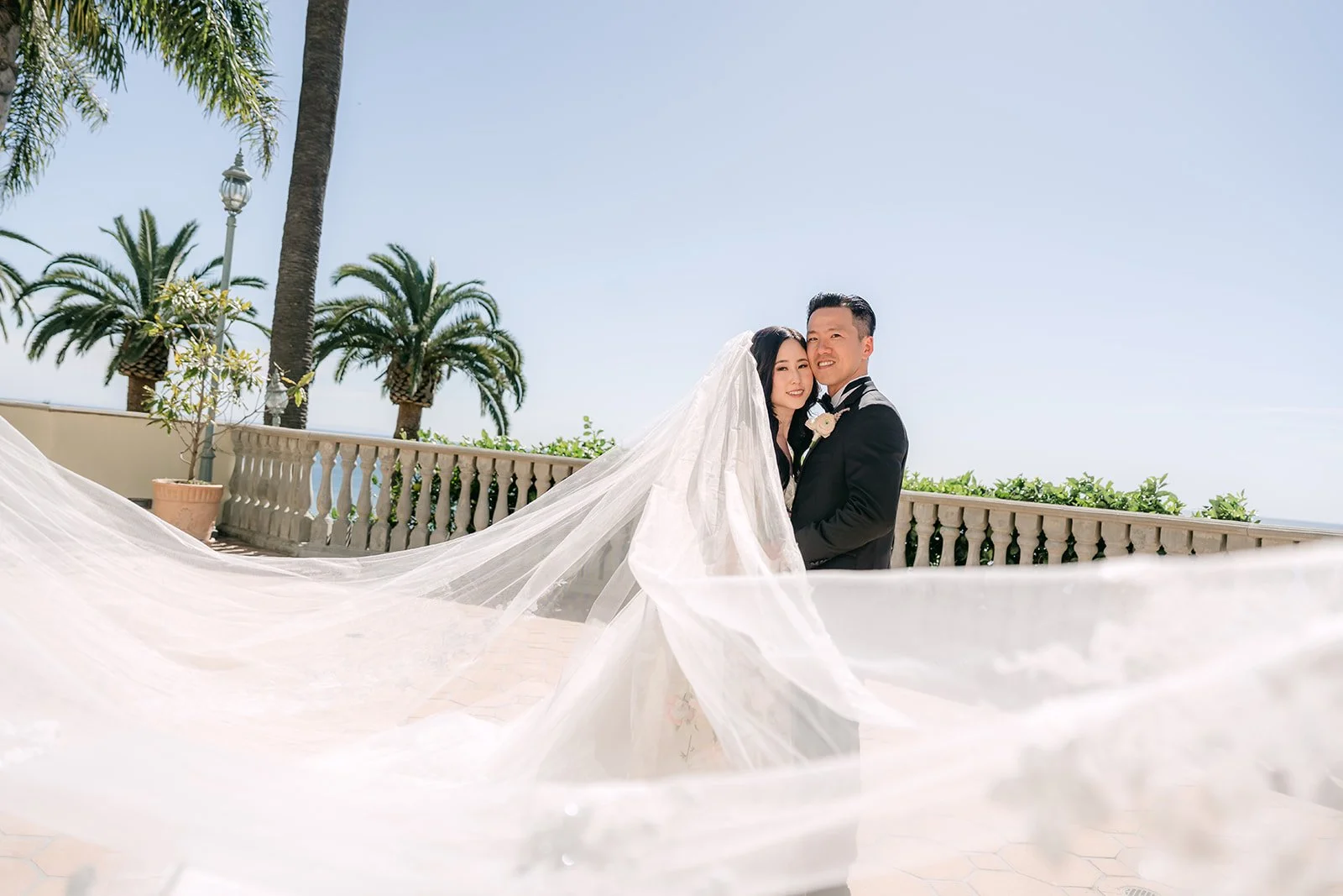 Couple embracing as the veil floats in the ocean breeze