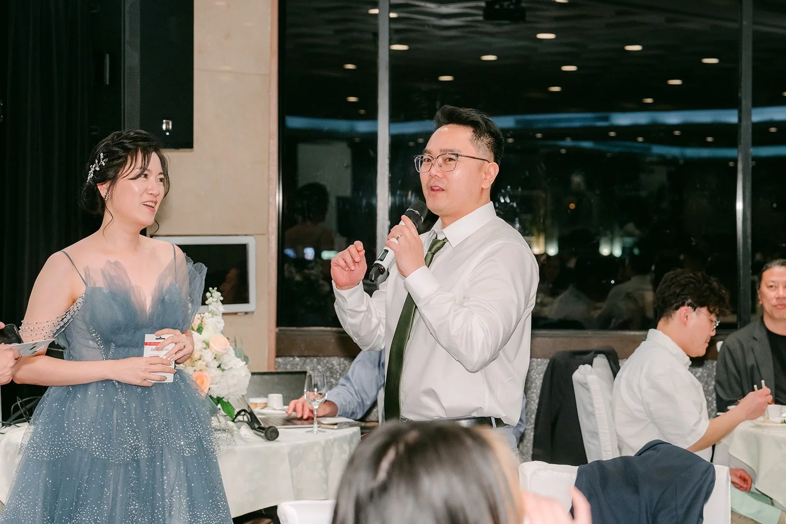 Eunice laughs with a guest holding the microphone during the reception games