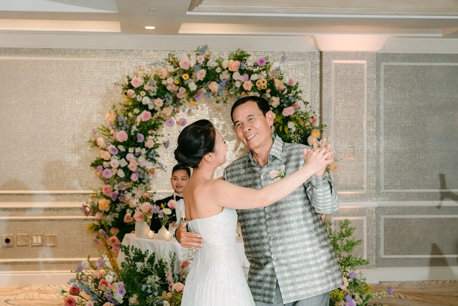Kylie sharing a parent dance by the floral arch